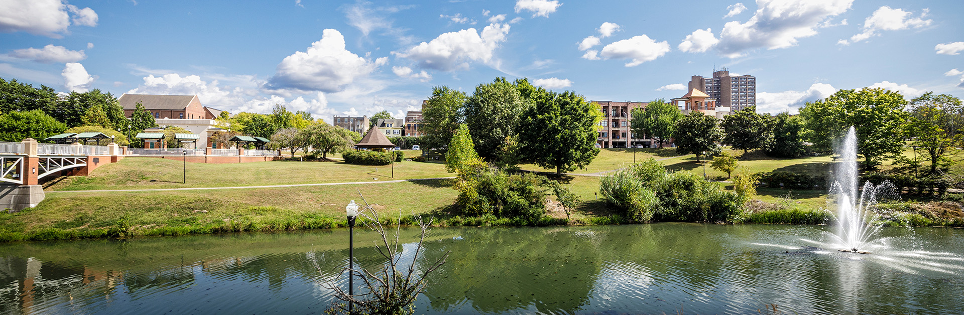 9 Sept. 2024-Maryville, TN: Wide angle skyscape view, from county library, of downtown with foot bridge on left and water feature on right.
